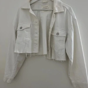Kort jeansjacka - Säljer en vit, kort jeansjacka från Stradivarius i storlek S. Den är knappt använd och i toppskick – perfekt för en fräsch och trendig stil!