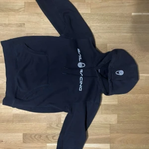 Sail racing hoodie - En svart Sail racing hoodie som är nästan i nyskick. Tröjan har för det mesta bara legat i garderoben och inte används. Pris kan diskuteras vid snabbaffär 