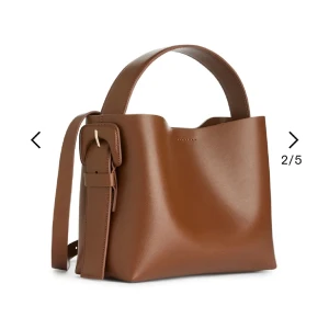 Arket väska  - Säljer min väska från Arket, super fin och inga defekter. Liten crossbody-väska tillverkad i dubbelt läder. Stylad med ett övre handtag och en avtagbar axelrem. Magnetförslutning och innerficka. Mått: 14X17X6 cm