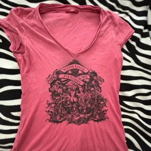 Rosa t-shirt med tryck - Säljer en cool rosa t-shirt från Edc by esprit  med ett stort svart tryck på framsidan som säger 'With Love, Passion and Care'. T-shirten har en v-ringad hals och korta ärmar. Perfekt för en avslappnad stil med lite edge! 