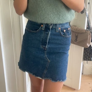 Blå jeanskjol från Levis - Supersnygg blå jeanskjol från Levis. Använd några få gånger så fortfarande i väldigt bra skick. Storlek 23, passar mig som har 24 vanligtvis. Köpt i butik