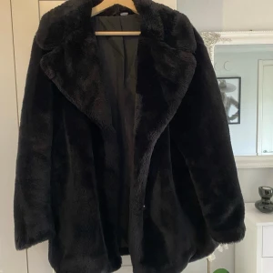 Svart pälsjacka - En supermysig svart pälsjacka som är perfekt för kyliga dagar. Den har en klassisk design med stora slag och är långärmad. Jackan är i jättebra skick men den har ett litet hål vid fickan nedtill som lätt kan lagas
