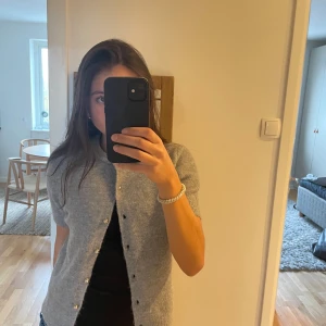 Stickad grå kofta - Säljer denna jättefina gråa kortärmade koftan med knappar ifrån Zara. Använd fåtal gånger och i jättebra skick. Jätte skönt material. Storlek M men är ganska liten i storleken. Passar mig som har XS-S🩶