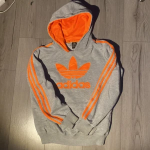 Grå adidas hoodie - Gro och ornage adidas hoodie storlek 164, passar ungefär XS och XXS, ok skick, använd många gånger