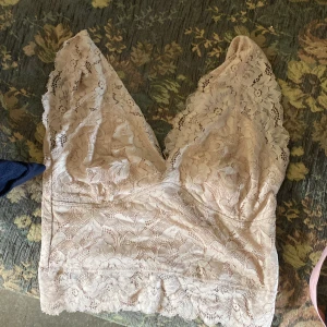 Beige spetslinne - Säljer ett superfint rosa spetslinne. Det är ärmlöst och har en v-ringad design. Perfekt för sommaren eller en festkväll. Linnet är i nyskick och har en tight passform. Det är spetsmaterial och har en romantisk känsla. Linnet är utlagt två gånger!