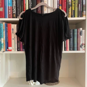 Svart topp från Gina Tricot - Säljer en svart topp från Gina Tricot i storlek M. Den har en cool design med öppna axlar och korta ärmar🥰