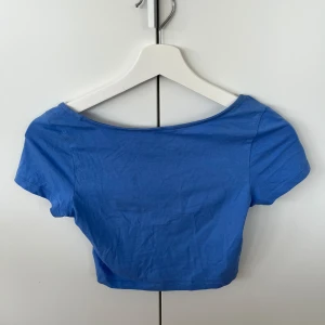 Blå crop top - Jättefin blå crop top med djup rygg från monki. Har tyvärr klippt bort lappen då den kliade men de är i väldigt fint skick, använd ett fåtal gånger.