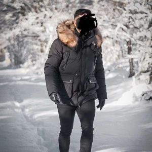 Svart dunjacka med äkta pälsluva - Säljer en svart dunjacka med avtagbar pälsluva. Jackan har flera praktiska fickor med knappar och dragkedja framtill. Perfekt för kalla vinterdagar med sin quiltade design och långa ärmar.