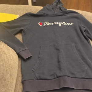 Mörkblå hoodie från Champion - Säljer en mörkblå hoodie från Champion med deras ikoniska logga på . Perfekt för en avslappnad stil.