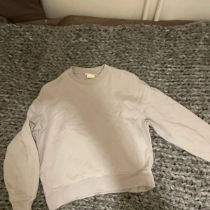 Grå vit typ beige ksk sweatshirt - Säljer en beige sweatshirt med rund hals och långa ärmar. Perfekt för en avslappnad stil. Tröjan är i en neutral färg som passar till det mesta.