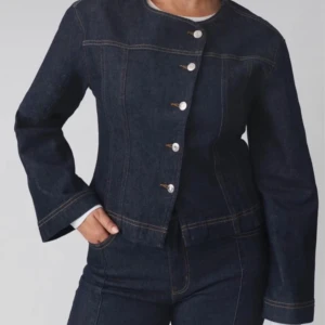 Mörkblå jeansjacka/jeans tröja med knappar - Snygg mörkblå jeansjacka/tröja med knappar framtill. Jackan har långa ärmar och en figurnära passform. Helt slutsåld. 