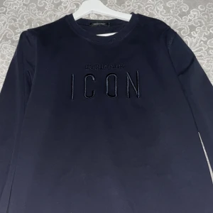 Svart långärmad tröja från Dsquared2 - Säljer en stilren svart långärmad tröja från Dsquared2 med texten 'ICON' broderad på framsidan. Perfekt för en trendig och avslappnad look.