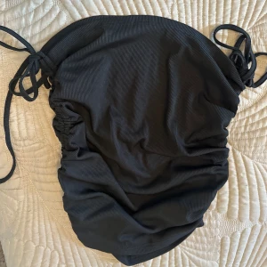 Svart ribbad bikini - Snygg svart ribbad bikini med knytband på sidorna. Perfekt för en stilren look vid poolen eller stranden.