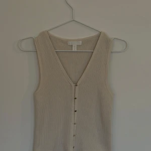 Väst ribbstickad - Ribbstickad cremefärgad v-ringad väst /linne med guldiga knappar