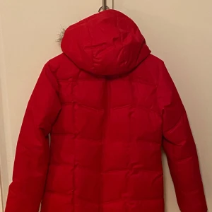 Röd vinterjacka från Etirel - Säljer en snygg röd vinterjacka från Etirel med pälskantad huva. Jackan har en dragkedja framtill och har praktiska fickor både på sidorna av jackan och innetill . Perfekt för kalla dagar.