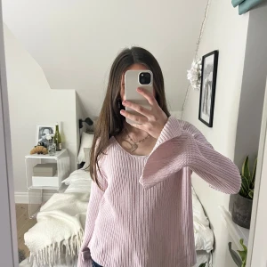 Rosa stickad tröja - Säljer en mysig rosa stickad tröja med långa ärmar och rosetter på armarna. Märket är clubxprs  storlek s.