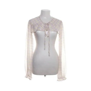 Rutig bolerotopp  - Säljer en unik rutig bolerotopp i lila och gul. Toppen har långa ärmar och knytning framtill. Perfekt för att lägga till en extra touch till din outfit.