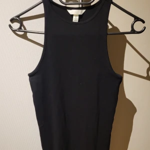 Svart ärmlös linnetopp - Säljer en stilren svart ärmlös linnetopp. Perfekt för lager-på-lager eller att bära som den är. Toppen har en enkel och klassisk design som passar till många olika outfits.