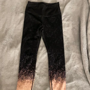 Svarta träningsthigts från H&M - Snygga svarta träningsbyxor från H&M med ett  leopardmönster som övergår i en rosa ton nedtill. Perfekta för träning eller en avslappnad dag. De är högmidjade och har en tight passform för extra komfort. I ett fint skick ⭐️
