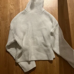 Vit ribbad polotröja - Säljer en stilren vit ribbad polotröja med långa ärmar. Perfekt för kyligare dagar med sin mysiga och varma design. Tröjan har en hög krage som ger extra värme och stil.