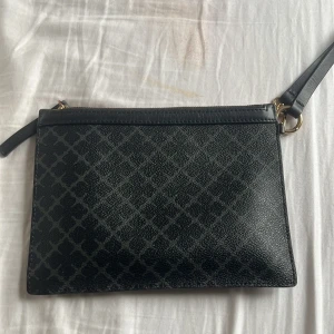 By malene Birger clutch  - Snygg by Malene Birger clucht. Den har en dragkedja. Insidan är fodrad i en brun nyans. Perfekt för att bära dina nödvändigheter med stil.