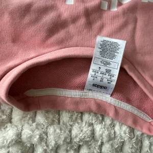 Rosa tröja från Adidas - Säljer en rosa tröja från Adidas med vit logga på framsidan. Tröjan har långa ärmar och är tillverkad i ett mjukt material. Perfekt för en avslappnad stil.