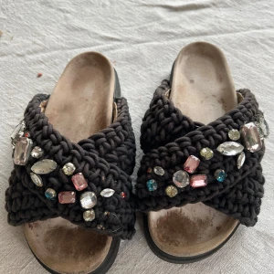 Svarta sandaler med pärlor från Inuikii - Unika svarta sandaler från Inuikii med en grovstickad design och dekorerade med färgglada pärlor. Perfekta för att ge en touch av glamour till din outfit. Sandalerna har en bekväm sula och en öppen tå.