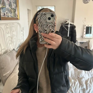 Svart pufferjacka från NA-KD - Säljer en svart pufferjacka från NA-KD. Jackan har en dragkedja framtill och en hög krage för extra värme. Den är perfekt för kyligare dagar och har en stilren design.