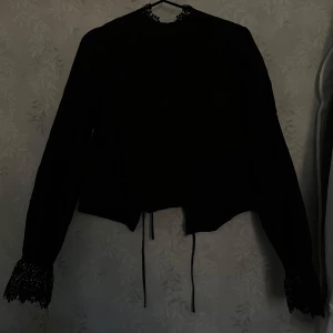 Svart öppen rygg blus  - Säljer nu denna svarta detaljrika öppen i ryggen blusen ifrån h&m. Säljer denna eftersom den inte kommer till andvändning längre, köpte den för något år sedan till ett evenemang jag skulle på men har inte andvänd den sedan sist. Detta matrialet den är gjord utav samlar lätt på sig damm så kan tänka mig att de är bra att rulla av den ibland. ❤️ skriv om minsta lilla funderingar!🥰