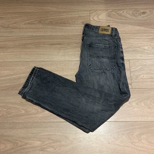 Grå jeans från Tommy Hilfiger - Snygga grå jeans från Tommy Hilfiger med klassisk femficksdesign. De har en rak passform och är tillverkade i slitstarkt denim. Perfekta för en avslappnad stil.