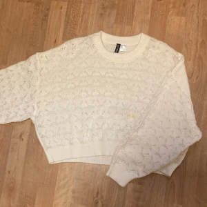 Vit stickad tröja från H&M - Säljer en söt vit stickad tröja från H&M. Tröjan är croppad med ett fint mönster och har långa ärmar. Perfekt för en mysig dag eller en stilren look. Det står storlek L men passar en M.