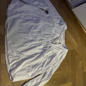 Vit långärmad blud med knytning - Säljer en vit långärmad blus med knytning vid halsen. Blusen har en lös passform och är tillverkad i ett lätt och bekvämt material. Perfekt för en avslappnad stil.