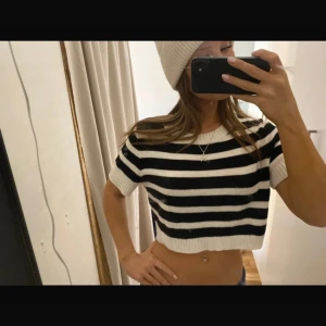 Svart och vit randig croppad tröja - Säljer en snygg svart och vit randig croppad tröja med korta ärmar. Perfekt för en trendig look. Tröjan är i ett mjukt material och har en avslappnad passform.
