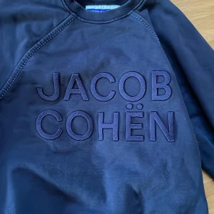 Jacob Cohen Tröja - Säljer denna marinblåa Jacob Cohen Crewneck i S. Tröjan är i toppskick och har inga defekter alls. Nypris ca 3000kr vårt pris 1100kr🤩.                  Äkthets bevis finns. Skriv vid minsta fundering.       Kolla profilen för 2 andra Jacob Cohen tröjor!!