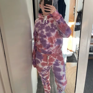 Tie-dye mjukisset från Madlady - Säljer ett färgglatt mjukisset i  tie-dye från Madlady i rosa och lila nyanser. Tröjan har en bekväm passform med långa ärmar och en justerbar huva med snören. 🌀