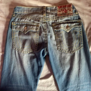 Blå jeans från True Religion - Snygga blå jeans från True Religion med klassisk femficksdesign och kontrasterande sömmar. De har en rak passform och är tillverkade i slitstarkt denim. Perfekta för en avslappnad stil. Insydda i midjan så de passar mig som brukar ha storlek 40 eller w30-31. går också lätt att sprätta de jag sytt om man vill det! skicka meddelande för mått eller fler bilder och pris går att diskutera ❣️