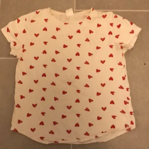 Vit t-shirt med röda hjärtan från Zara - ❤️❤️Söt vit t-shirt från Zara med röda hjärtan över hela tyget. Perfekt för en lekfull och kärleksfull stil. Kortärmad och bekväm passform.❤️❤️