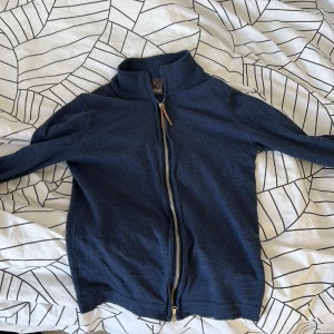 Mörkblå tröja från Oscar Jacobsson  - Säljer en stilren mörkblå tröja från Oscar Jacobson i storlek S. Tröjan har en praktisk dragkedja framtill och är tillverkad i ett mjukt material. Perfekt för milda dagar 