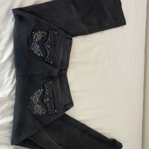 Svarta jeans med detaljer från Madlady - Snygga svarta jeans från Madlady med coola detaljer på bakfickorna. Jeansen har en bootcut-stil och är dekorerade med paljetter. Passar till vilken outfit somhelst. Säljer då jag råka beställa i fel storlek och drog av lappen, jag är 162 och brukar ha stl EU32 short. Byxorna är bra i längden men passar någon lite kurvigare än mig. HELT OANVÄNDA. Nypris 799kr