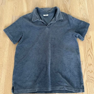 Blå frotté piké - Säljer en grå frotté piké från Kappahl som är blå. (Frotté piké är annat ord för handdukströja) Har krage utan knappar.