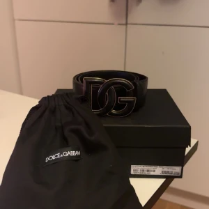 Svart Cintura skärp från Dolce & Gabbana - Snyggt svart skärp från Dolce & Gabbana med en stor DG-logotyp i metall som spänne. Skärpet är tillverkat i skinn och kommer med en elegant förvaringspåse och originalförpackning. Perfekt för att ge en lyxig touch till din outfit. Nypris 4500kr. Kom Pm för frågor