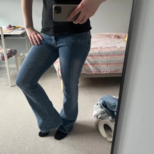 Blå bootcut jeans med detaljer - Snygga blå bootcut jeans med glittriga detaljer i fram. Low/mid-waist!  Lite stretchigre tyg än vanligt jeanstyg!💕Postar snabbt!  midjemått: 39 cm innerbenslängd: 81 cm benbredd längst ner: 26,5 cm