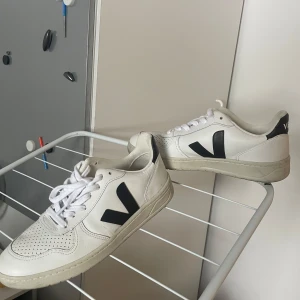 Veja sneakers - Snygga vita sneakers från Veja med svarta detaljer och snörning. Perfekta för en stilren look. Tillverkade i skinn med en klassisk design.