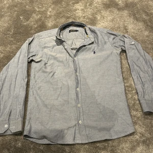  Skjorta från Polo Ralph Lauren -  Polo Ralph Lauren Skjorta  Snygg ljusblå skjorta från Polo Ralph Lauren med klassisk krage, broderad logga och långa ärmar. Knappar framtill för en stilren look! 👔✨  Nypris: 1 599 kr💰 Vårt pris: Endast 499 kr! ⚡️ 