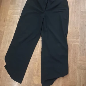 Svarta lågmidjade kostymbyxor från Bershka - Snygga svarta kostymbyxor från Bershka med en klassisk design. Byxorna har en knapp och dragkedja framtill för enkel stängning. Perfekta för en stilren look. Lågmidjade