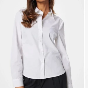 Vit skjorta från Bubbleroom - Klassisk vit skjorta från Bubbleroom i 100% ekologisk bomull. Skjortan har långa ärmar och knappar framtill, perfekt för en stilren look. Tillverkad i ett mjukt och bekvämt material.