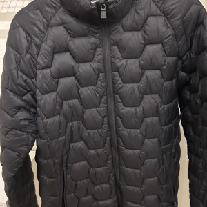 Svart quiltad jacka  - Säljer en svart quiltad jacka med dragkedja framtill. Jackan har en cool hexagonmönstrad design och långa ärmar. Perfekt för kyligare dagar!