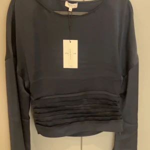 Mörkblå långärmad topp från H&M - Snygg mörkblå långärmad topp med stilrena veckdetaljer på framsidan. Perfekt för en elegant look. Toppen är tillverkad i ett mjukt och följsamt material.