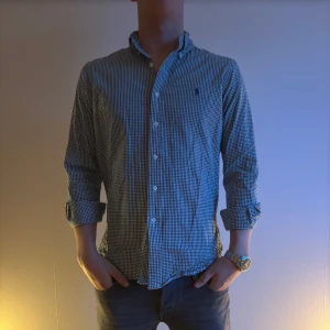 Rutig skjorta från Ralph Lauren - Snygg rutig skjorta från Ralph Lauren i blått och knappar framtill. Perfekt för en stilren look.