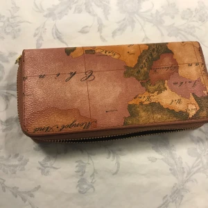 Plånbok med kartmönster - Säljer en unik plånbok med ett vintage kartmönster. Plånboken har flera fack för kort och en dragkedja för mynt. Perfekt för dig som gillar en äventyrlig stil! Helt ny 